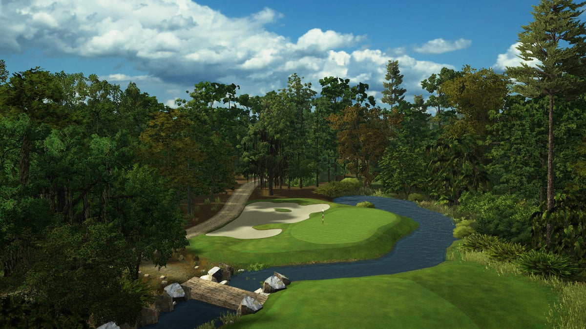 Golf course with green, bunkers, and trees under a blue sky with clouds.