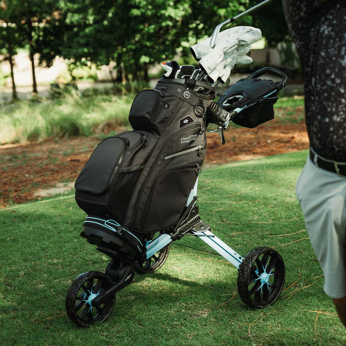 Bag Boy Nitron golf cart, ice blue, with black Chiller Pro cooler bag, lifestyle photo