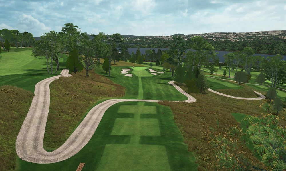 Golf course with a winding path and trees under a blue sky.
